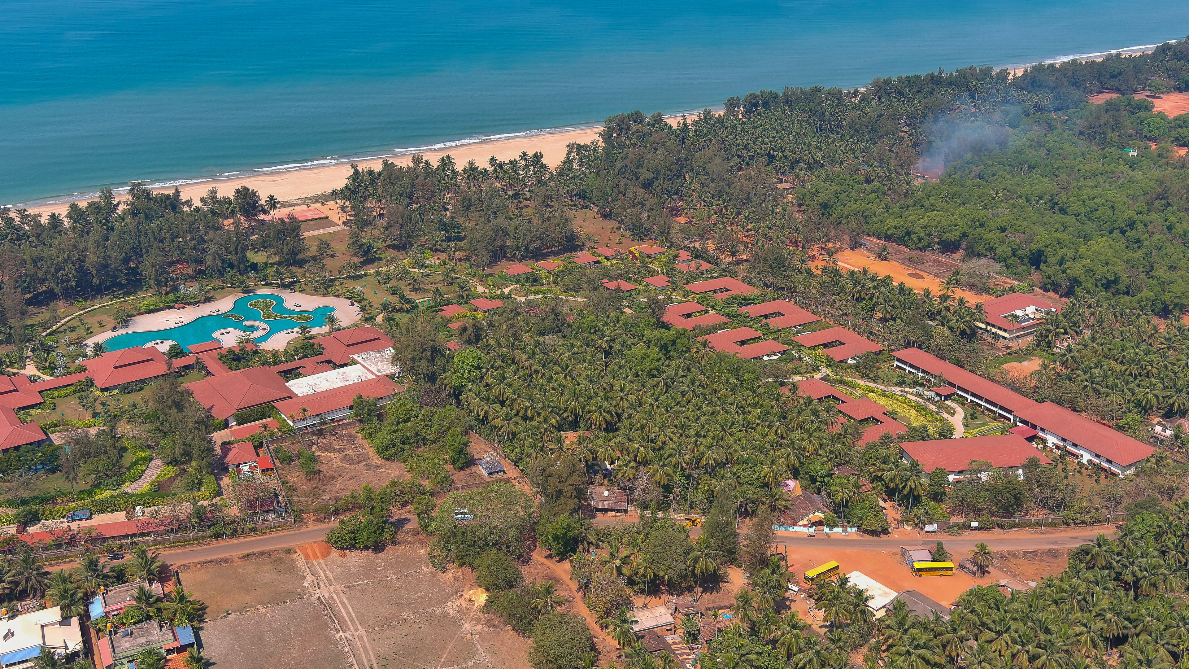 Luchtbeeld van een resort met meerdere gebouwen, een zwembad en een strand.
