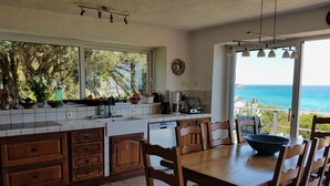 Una cocina con una isla grande, armarios de madera y vista al océano.