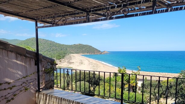 Una terraza con asientos al aire libre, una copa de vino y vistas al mar.