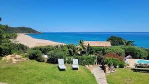 A coastal property with a clear view of the sea, a sandy beach, and a stone pathway leading to a seating area with two chairs. -  Exclusive granite villa DIRECTLY on the beach, sea and mountain panorama, pool (Zonza)