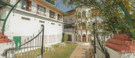 A courtyard with a white building, green railings, and a tiled pathway.