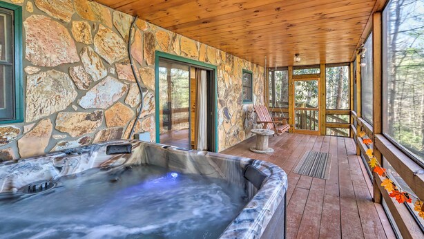Un espace spa doté d’un mur en pierre, d’un plafond en bois et d’un bain à remous.