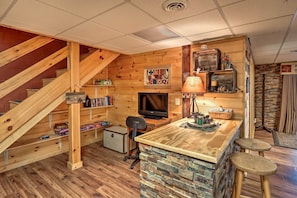 Cozy cabin interior with a wooden staircase, comfortable seating area, and a desk for work.