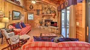 Un intérieur de chalet chaleureux avec une cheminée, des meubles à motifs écossais et un mur d’accent en pierre.