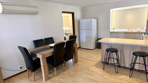 A compact kitchen with a dining area, a refrigerator, and a bar counter with stools.