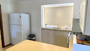 A compact kitchen with a refrigerator, a sink, and a stove.
