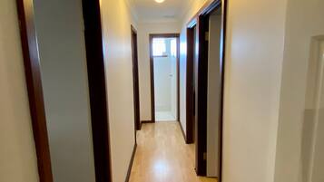 A narrow hallway with wooden doors and a light-colored floor.