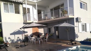 Un espace aménagé au bord de la piscine, avec une table et des chaises, un petit chien et un jouet d’enfant.