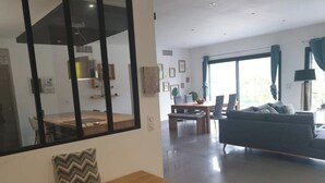 Una zona d'estar àmplia amb taula de dinar, sofà i una finestra gran.