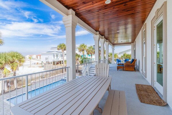 A covered outdoor area with a pool, wooden deck, and seating.