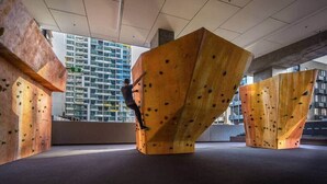 Een klimmuur met daaraan een klimmer, voor een modern gebouw.