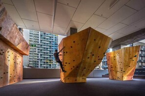 Een klimmuur met daaraan een klimmer, voor een modern gebouw.