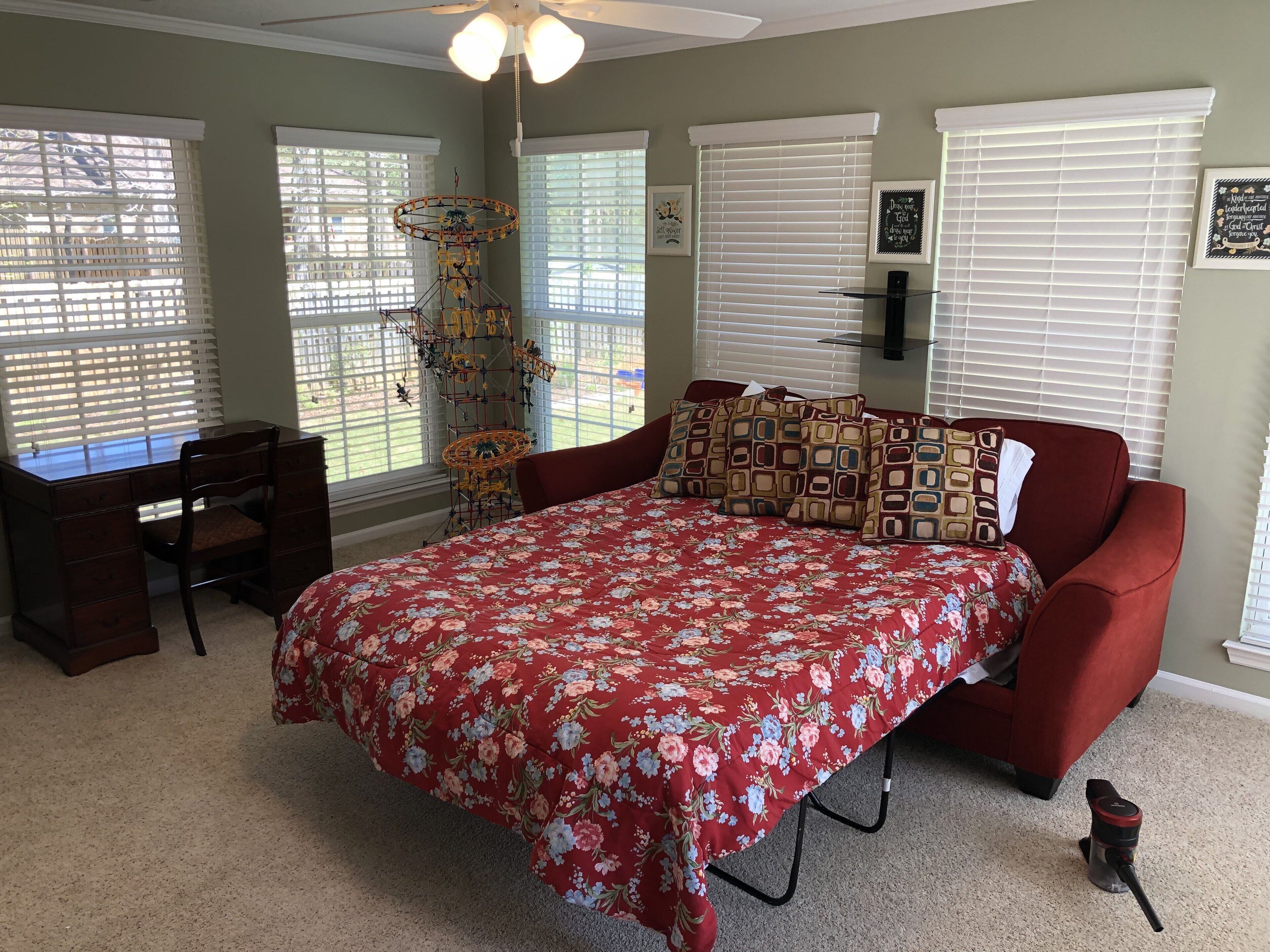 A bedroom with a bed, a desk, and a chair.