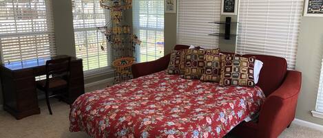 A bedroom with a bed, a desk, and a chair.