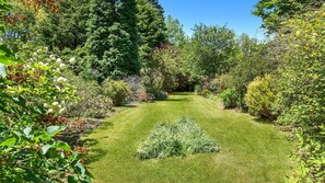 A well-maintained garden with a variety of shrubs and trees, a neatly trimmed lawn, and a clear pathway.