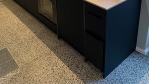 Moderni keittiö, jossa on keskeinen saareke, mustat kaapit ja työtaso, jossa on kahvinkeitin.