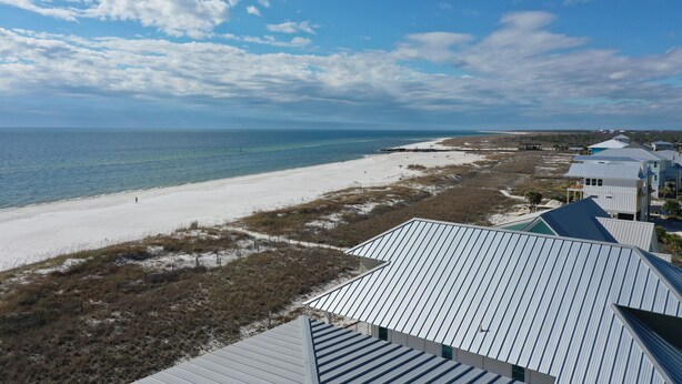 A coastal view with a beach, a few buildings, and a clear sky.