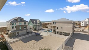 A beachfront property with multiple houses, a swimming pool, and a sandy beach area.