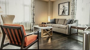 A modern living room with a sofa, armchair, coffee table, and a lamp.