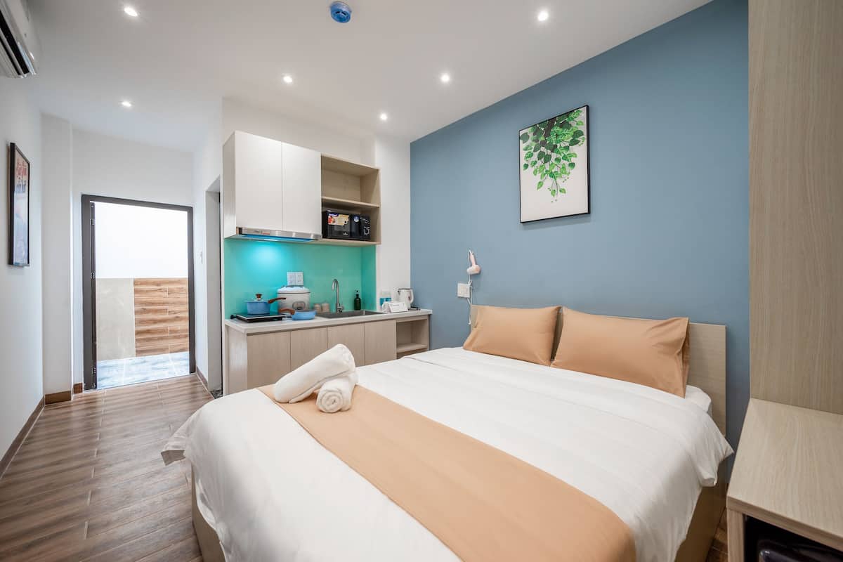 Quarto de hotel com cama, cozinha compacta, banheiro e vista para o exterior.