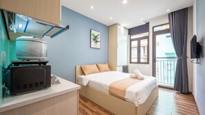 Une chambre d’hôtel moderne équipée d’un lit, d’une télévision, d’un petit coin cuisine et d’un balcon avec vue.