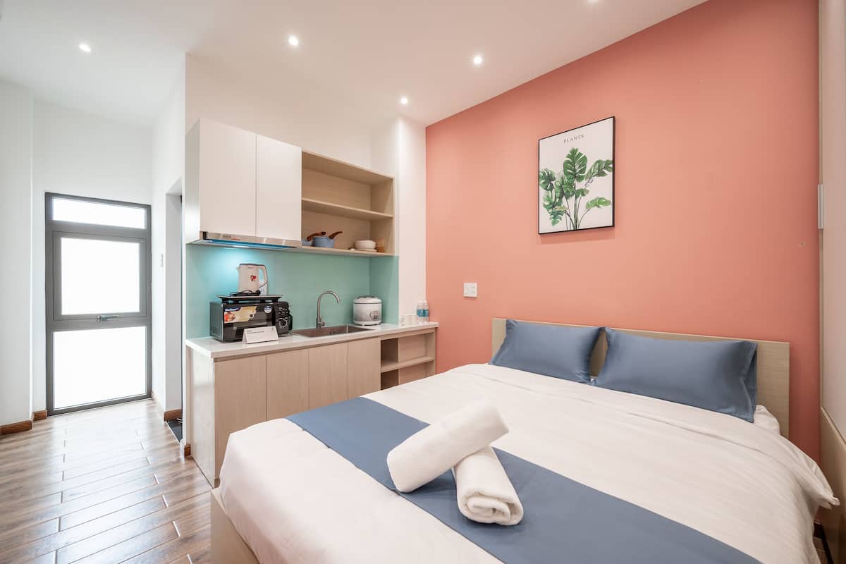 Quarto de hotel moderno com uma cama grande, cozinha compacta e vista para o exterior.
