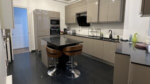 Een moderne keuken met een centraal eiland, roestvrijstalen apparatuur en een strak design.