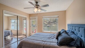 Un dormitorio con una cama grande, ventilador de techo y vistas al lago a través de la ventana.