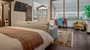 A bedroom with a large bed, a desk, a chair, and a TV.