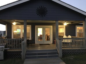 Une véranda couverte avec une terrasse en bois, un barbecue et un coin repas comprenant des chaises et une table.
