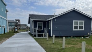 Et boligområde med en betonsti, der fører hen til et hus med veranda.