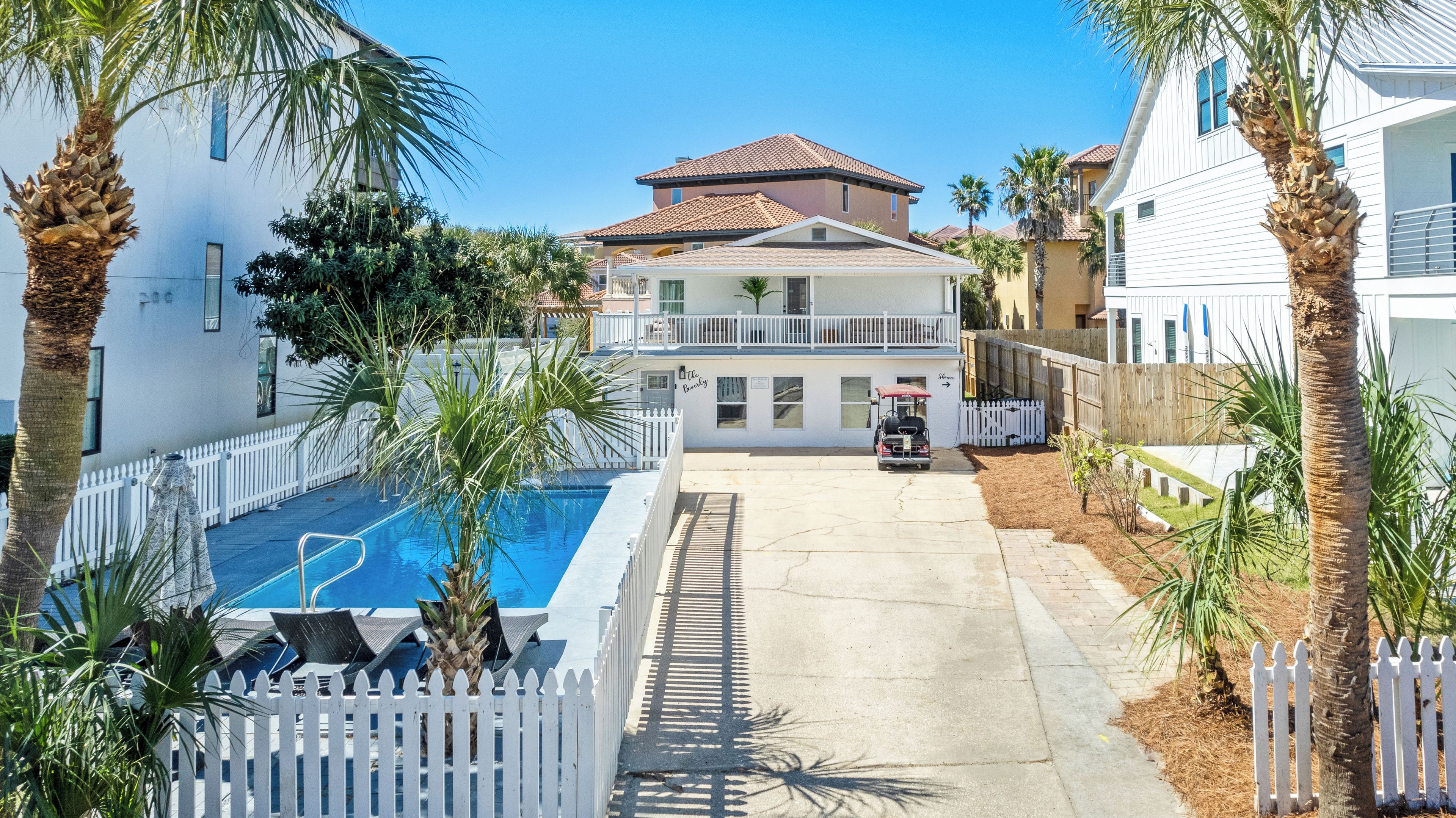 Ein Wohngebiet mit Swimmingpool, weißem Zaun und Grill.