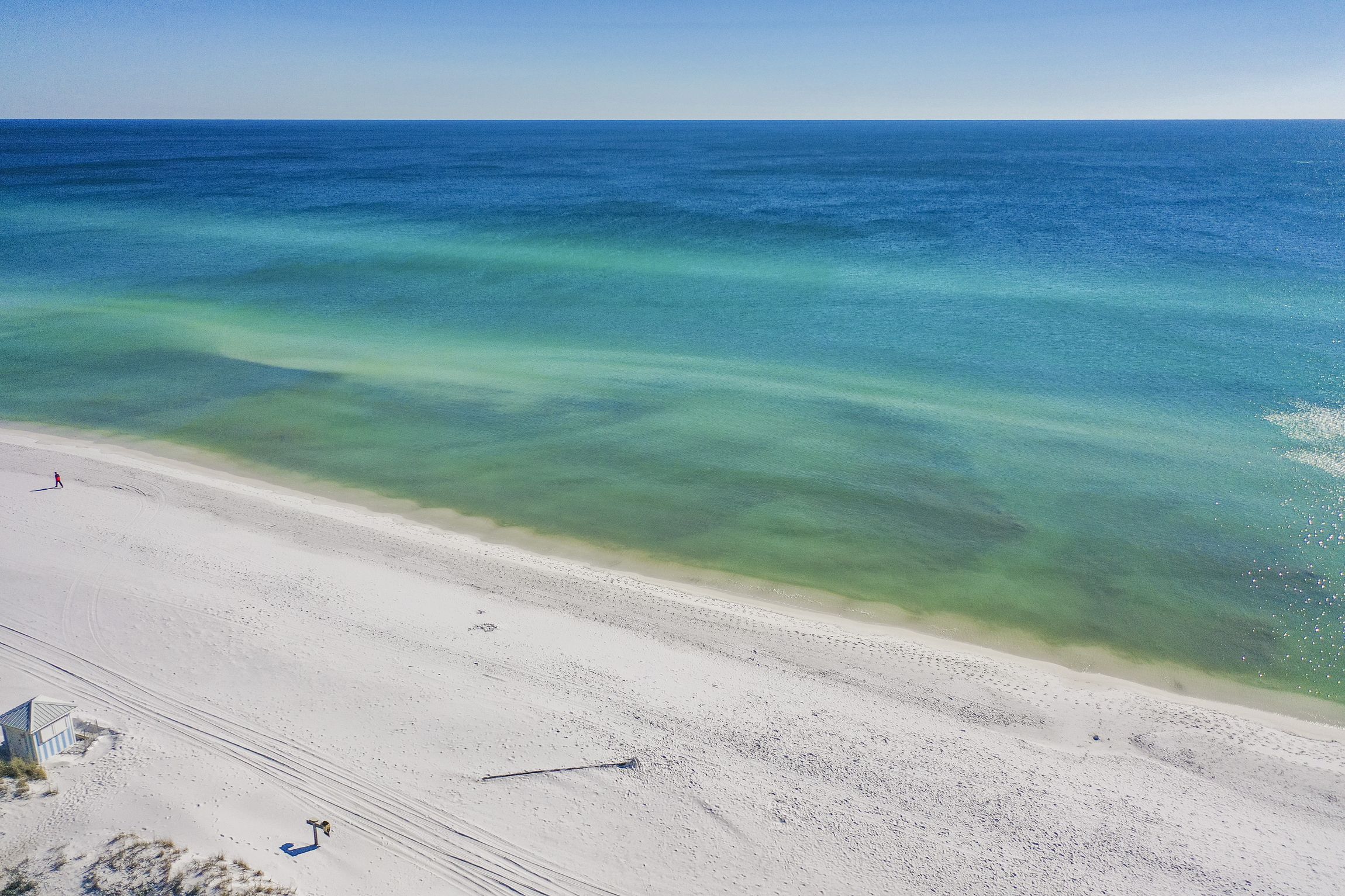 A beach with clear turquoise water and white sand.