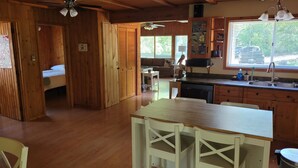Un interior de madera con cocina, mesa de comedor y un dormitorio con cama.