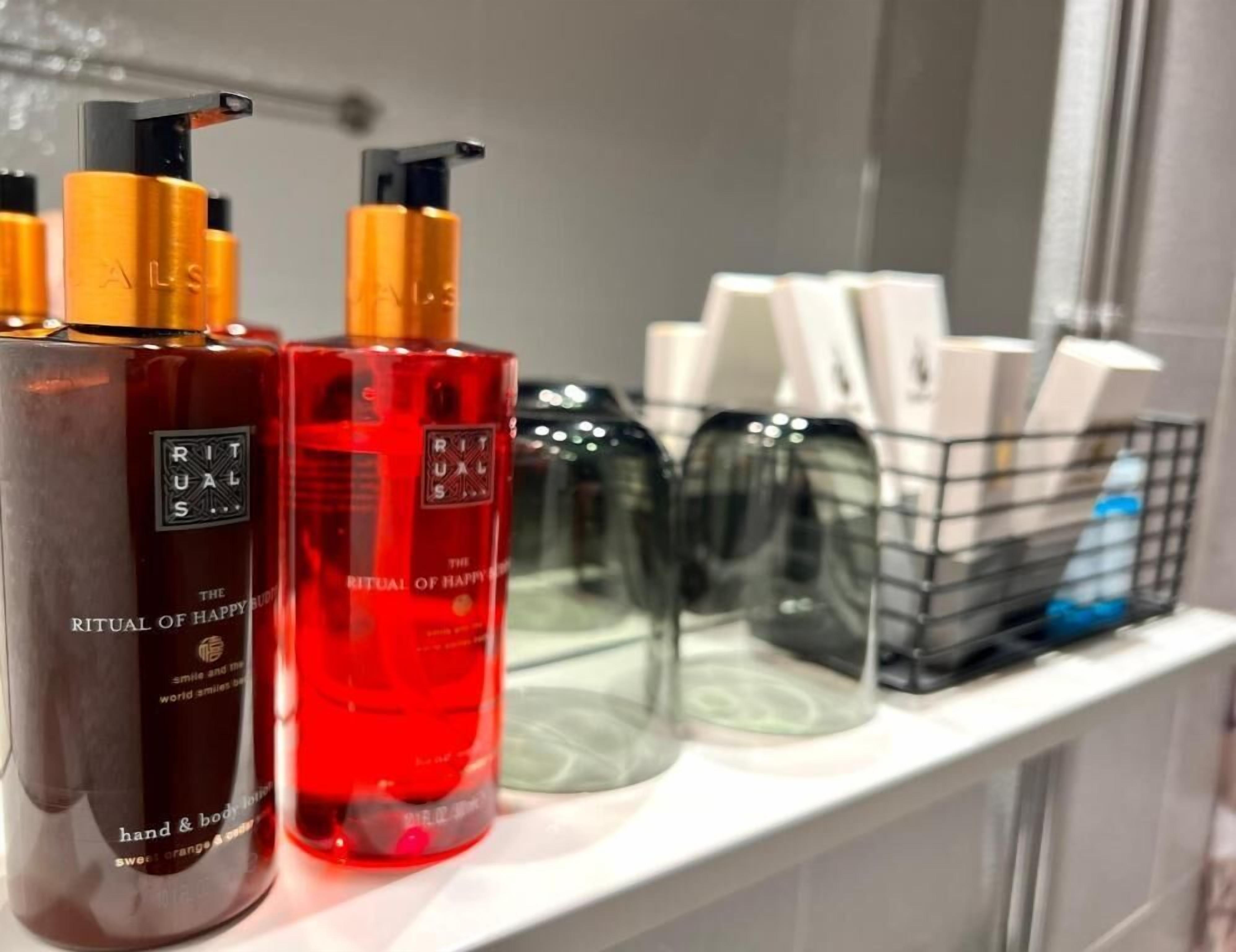 Une étagère de salle de bain contenant divers produits de toilette, notamment des flacons de lotion pour le corps de la marque Rituals et un récipient noir.