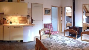 A cozy kitchen with a dining area, wooden cabinets, and a table with a patterned tablecloth. - THE THREE SNAP HOOKS (Champagny-en-Vanoise)