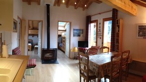 A cozy interior with a wooden dining table, chairs, a red sofa, a fireplace, and a bookshelf. - THE THREE SNAP HOOKS (Champagny-en-Vanoise)