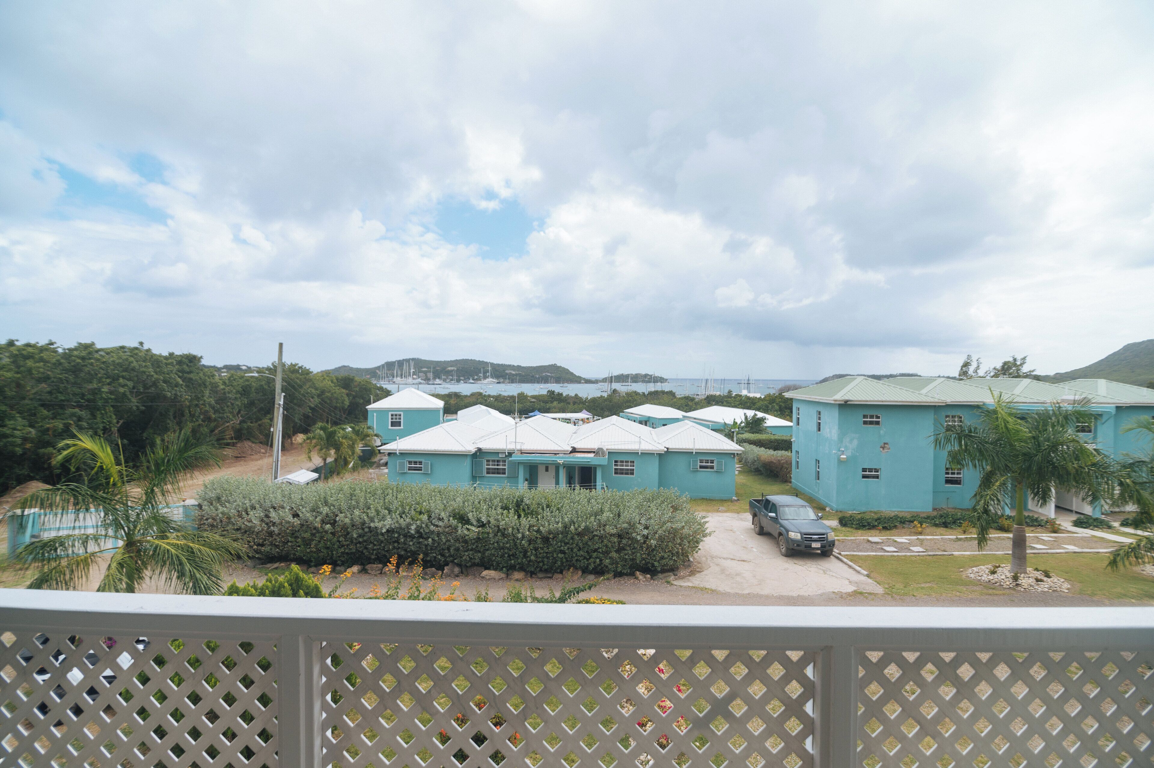 A view of a residential area with multiple blue houses, a paved driveway, and a palm tree.