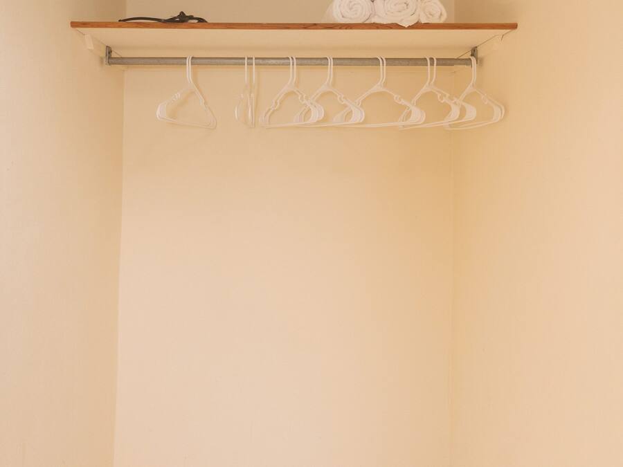 A small, empty closet with a wooden shelf and a metal rod for hanging clothes.