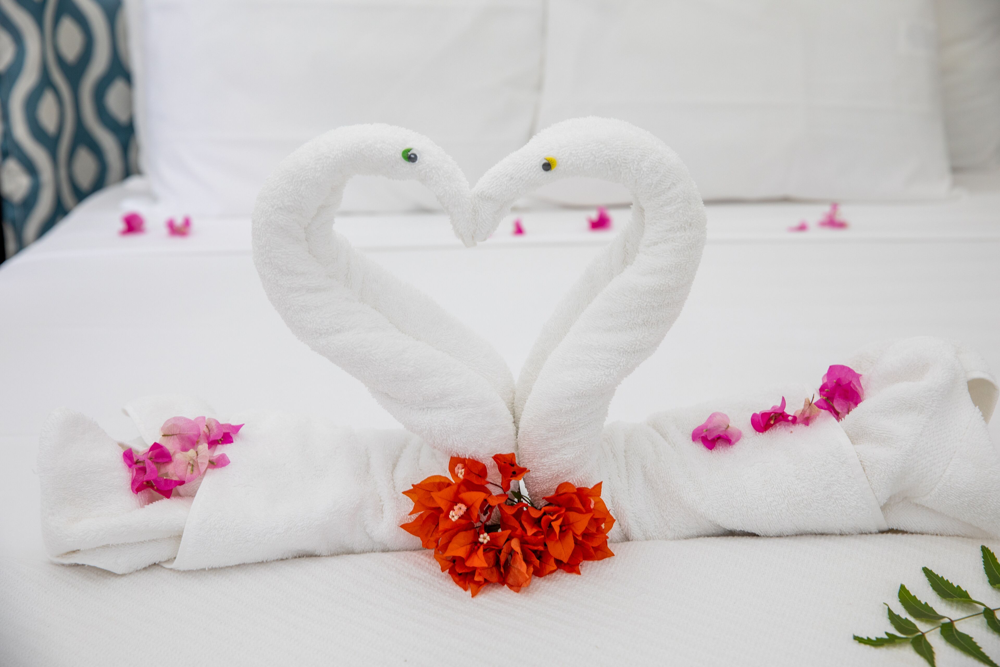 A bed with white linens and two swan-shaped towels.
