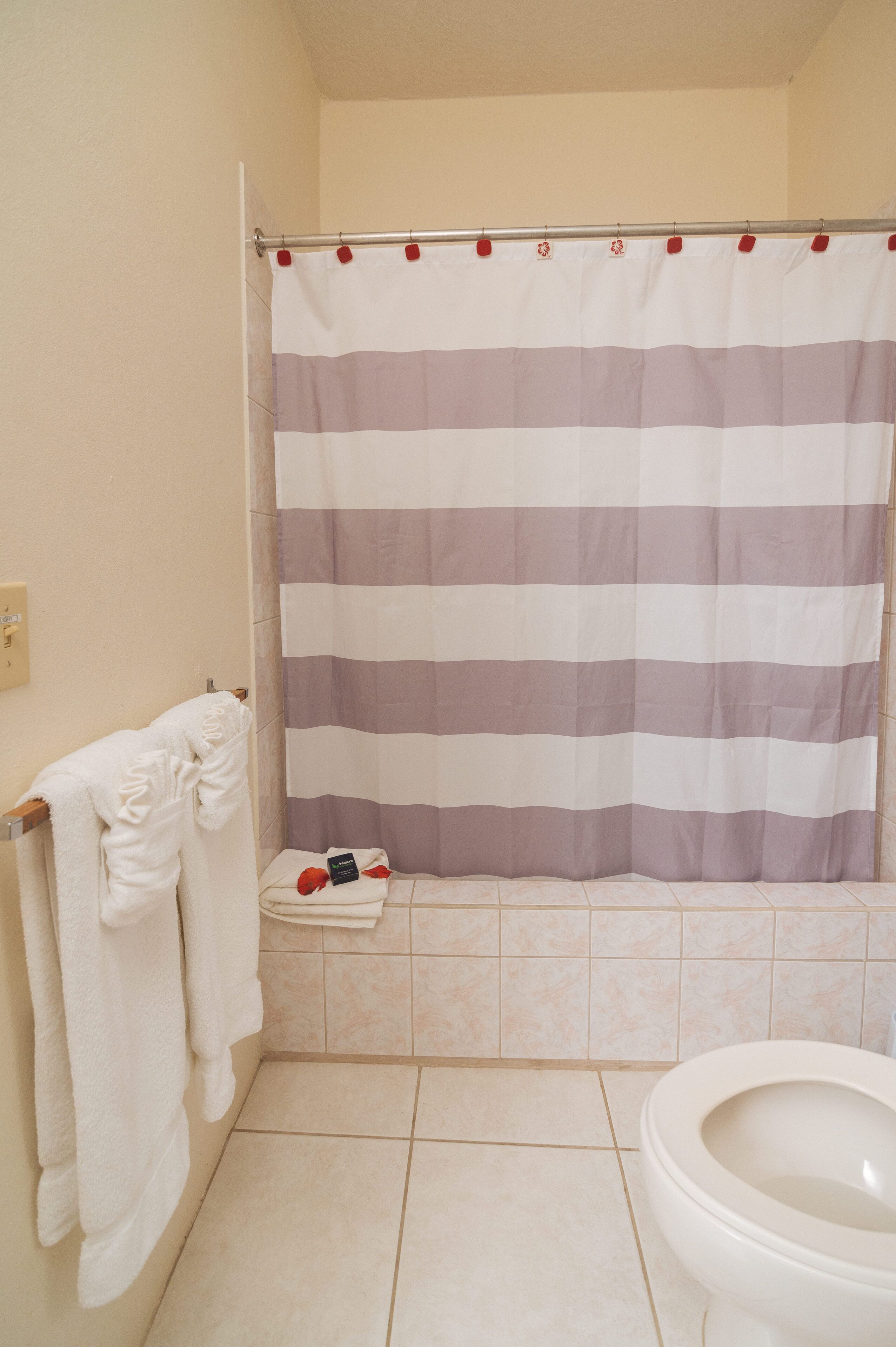 A bathroom with a striped shower curtain, a white toilet, and a towel rack with towels.