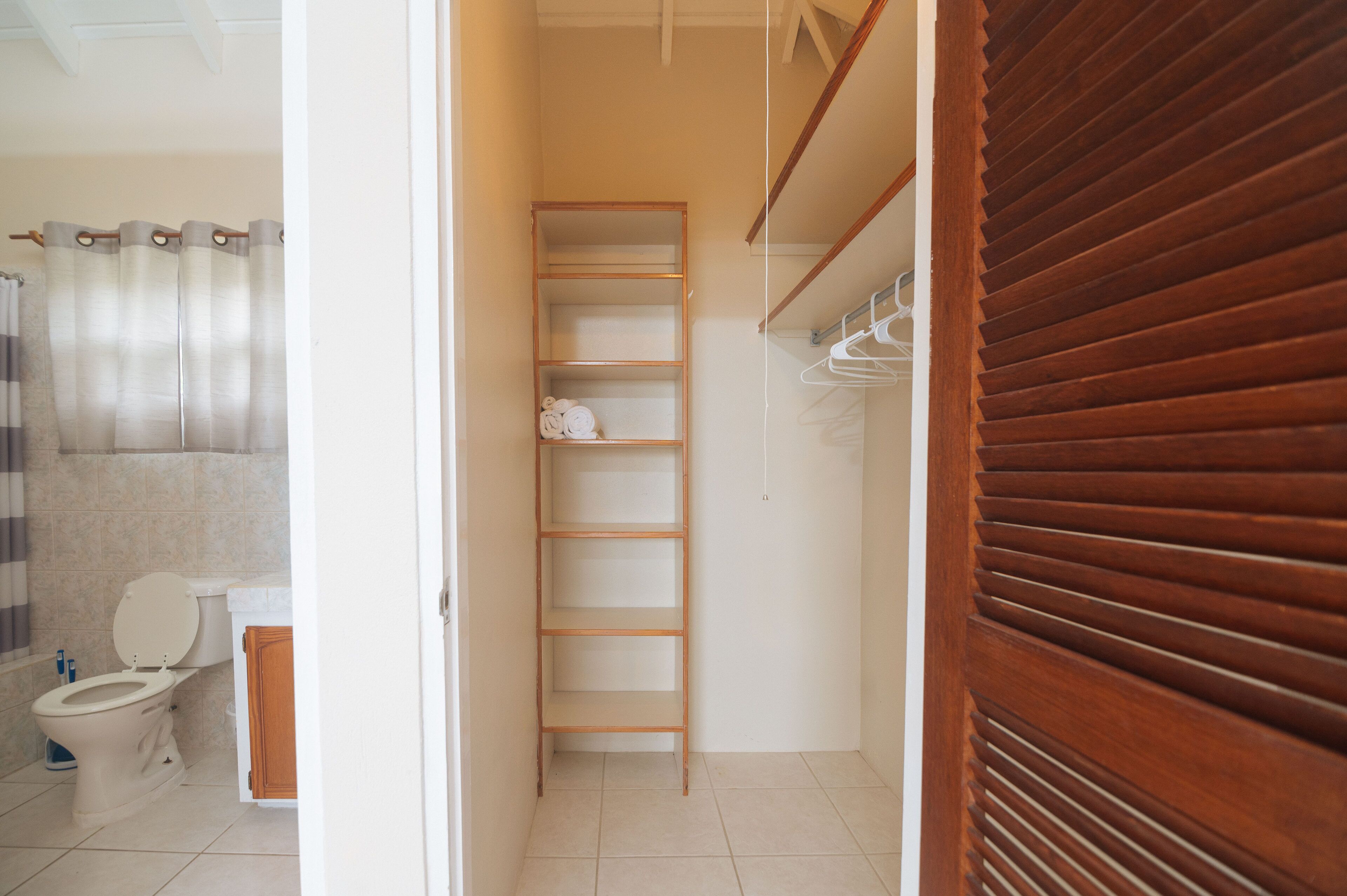 Un bagno con il water, una doccia e un mobiletto portaoggetti in legno.