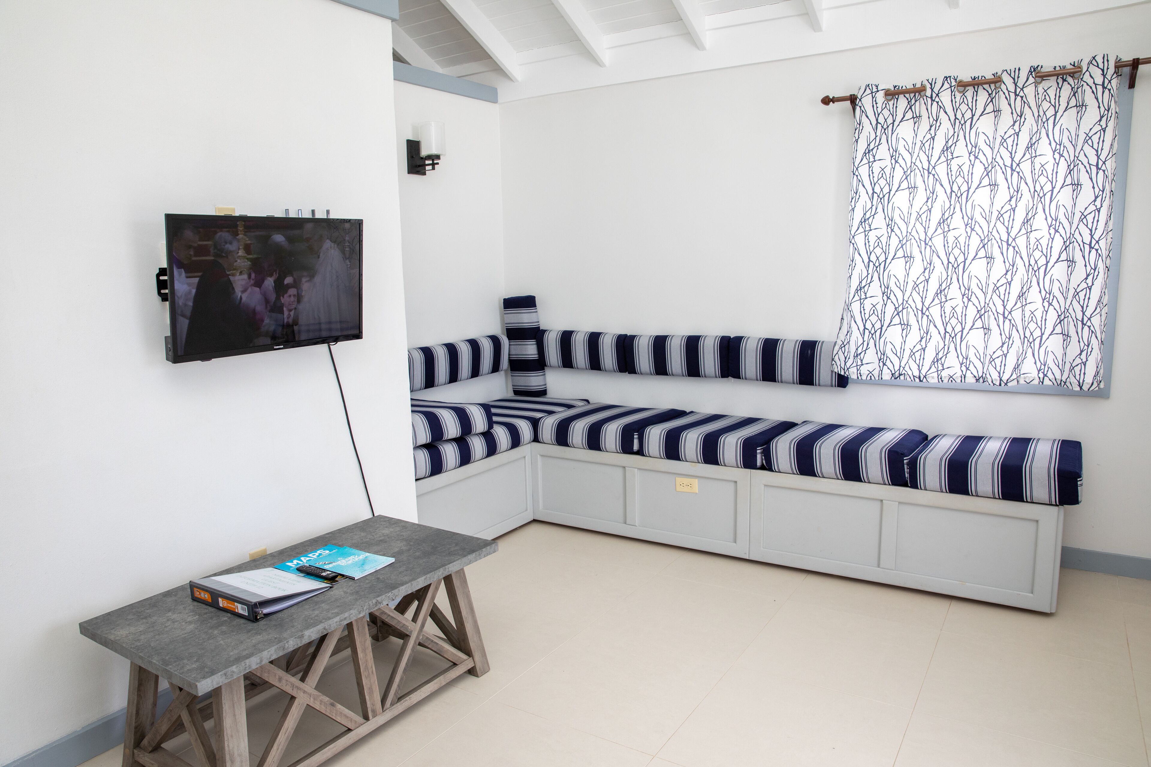 Une pièce moderne dotée d’une banquette intégrée, d’un téléviseur fixé au mur et d’une petite table sur laquelle repose un livre.