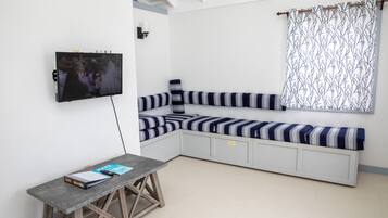 Une pièce moderne dotée d’une banquette intégrée, d’un téléviseur fixé au mur et d’une petite table sur laquelle repose un livre.