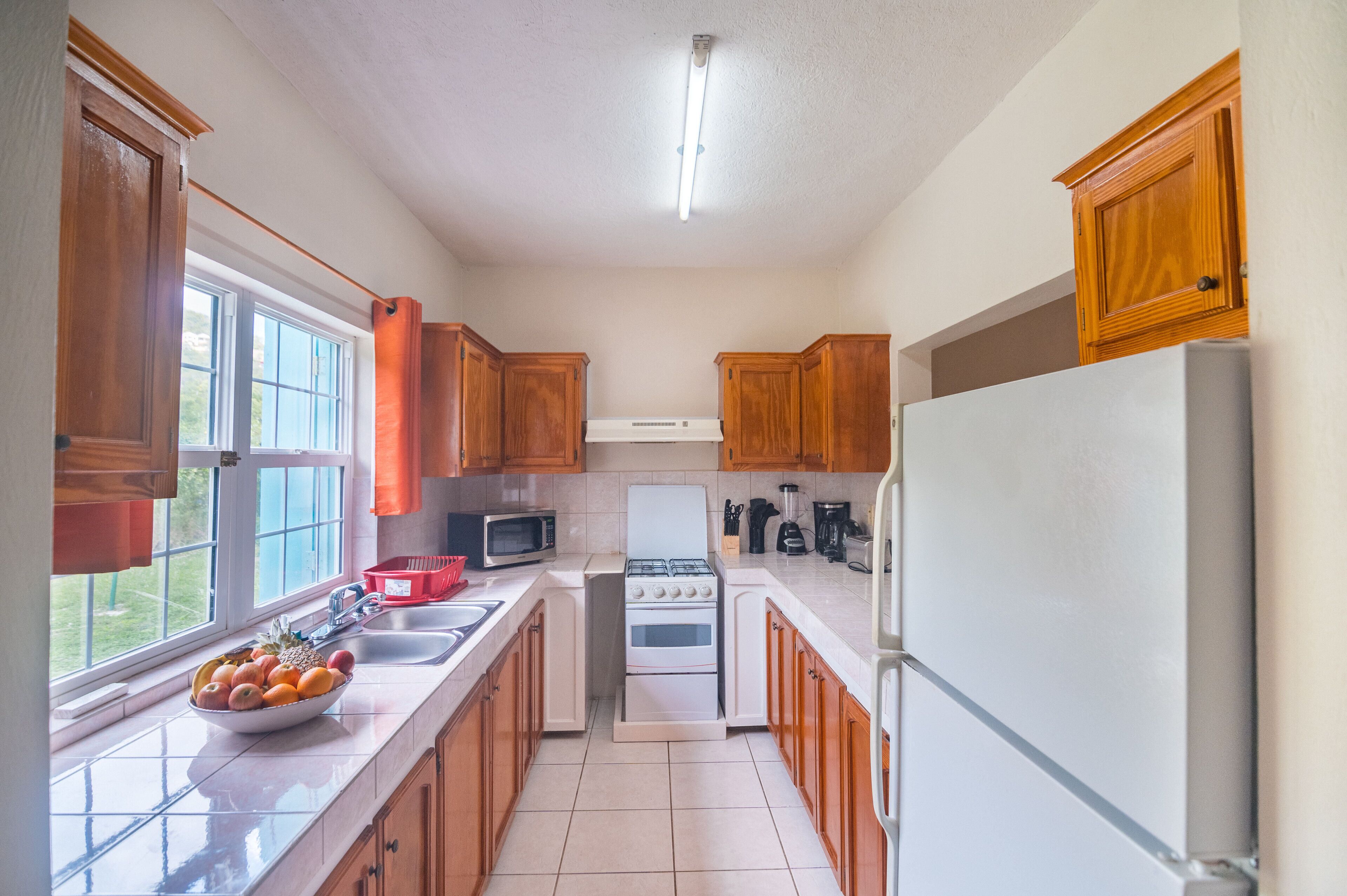 Une cuisine avec des meubles de rangement en bois, une cuisinière, un four à micro-ondes et un réfrig érateur.