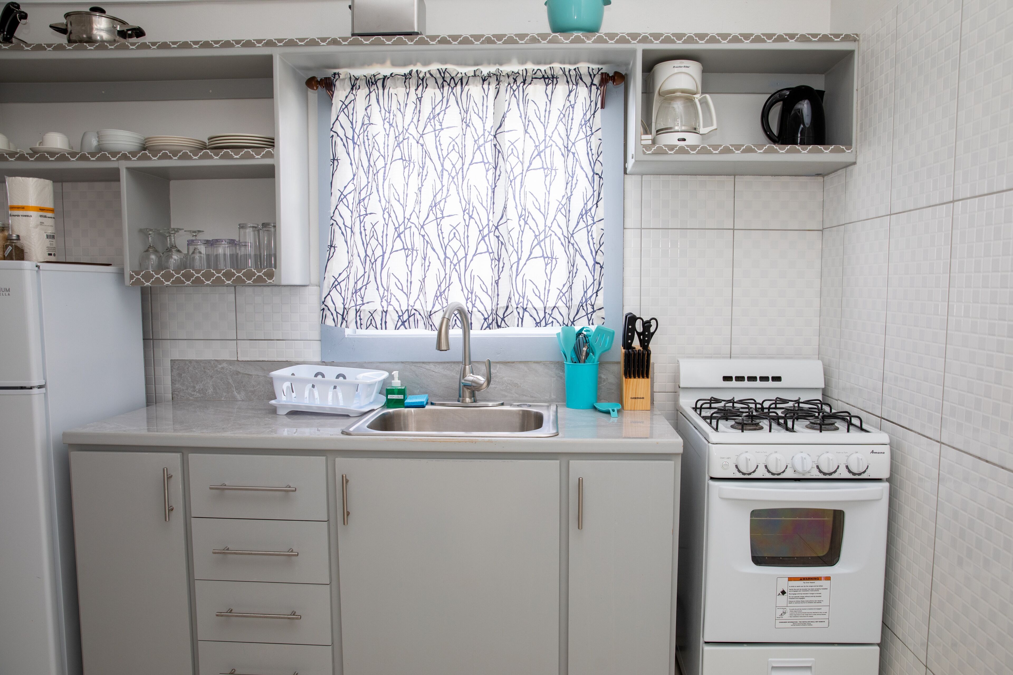 A kitchen with a sink, stove, and cabinets.