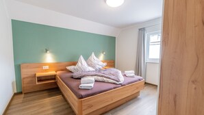 Une chambre à coucher moderne avec un lit en bois, une table de chevet et une lampe fixée au mur.
