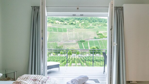 Une chambre d’hôtel avec un lit et une vue sur un paysage verdoyant, accessible depuis un balcon.