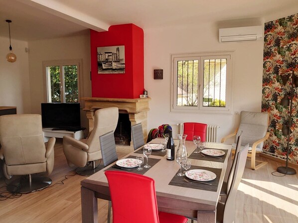 A dining area with a table set for four, a fireplace, and a television in the corner.