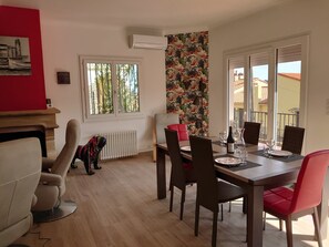 A dining area with a wooden table, red chairs, and a view of the outside.
